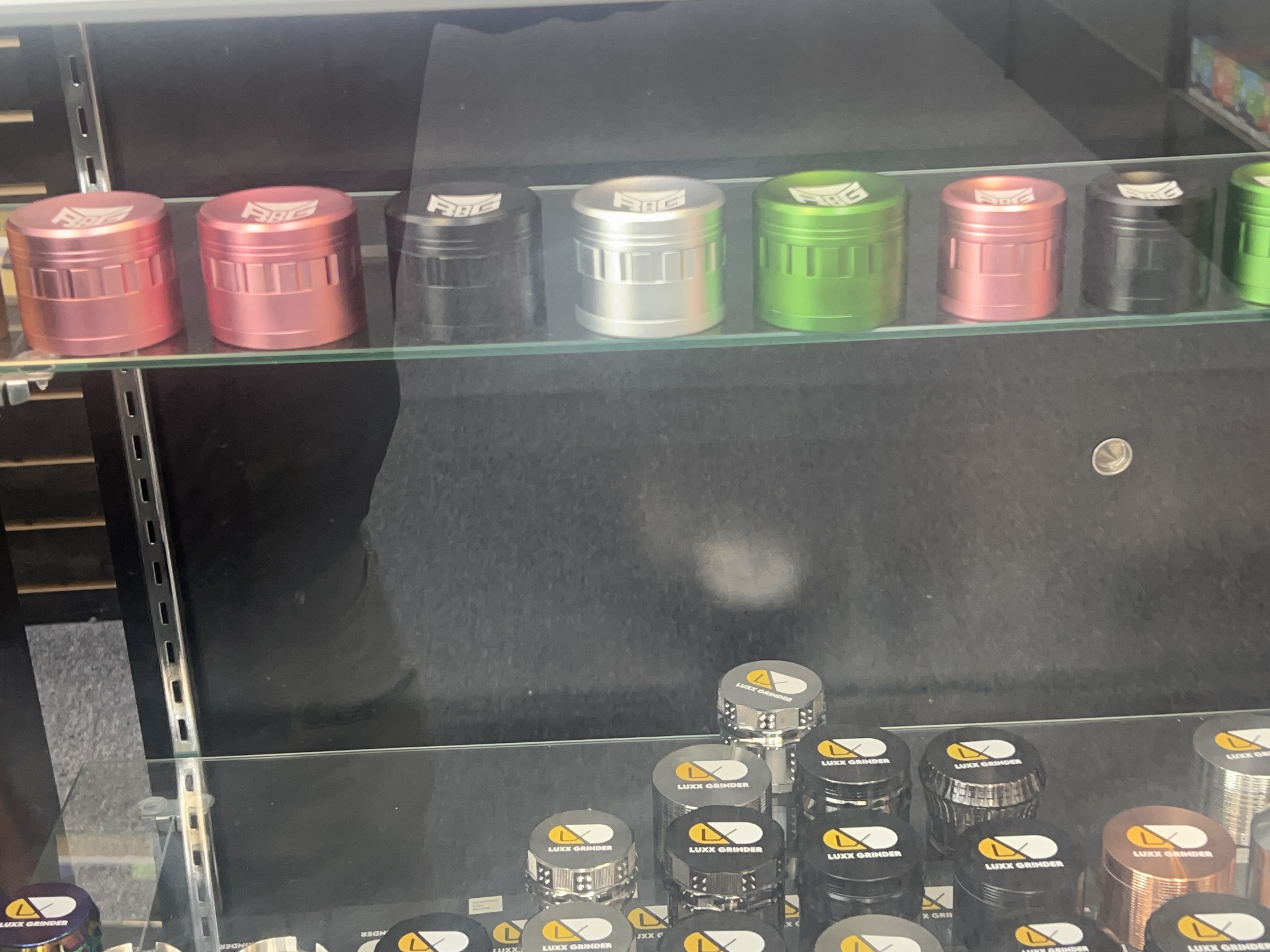 Colorful herb grinders displayed on glass shelves in a store