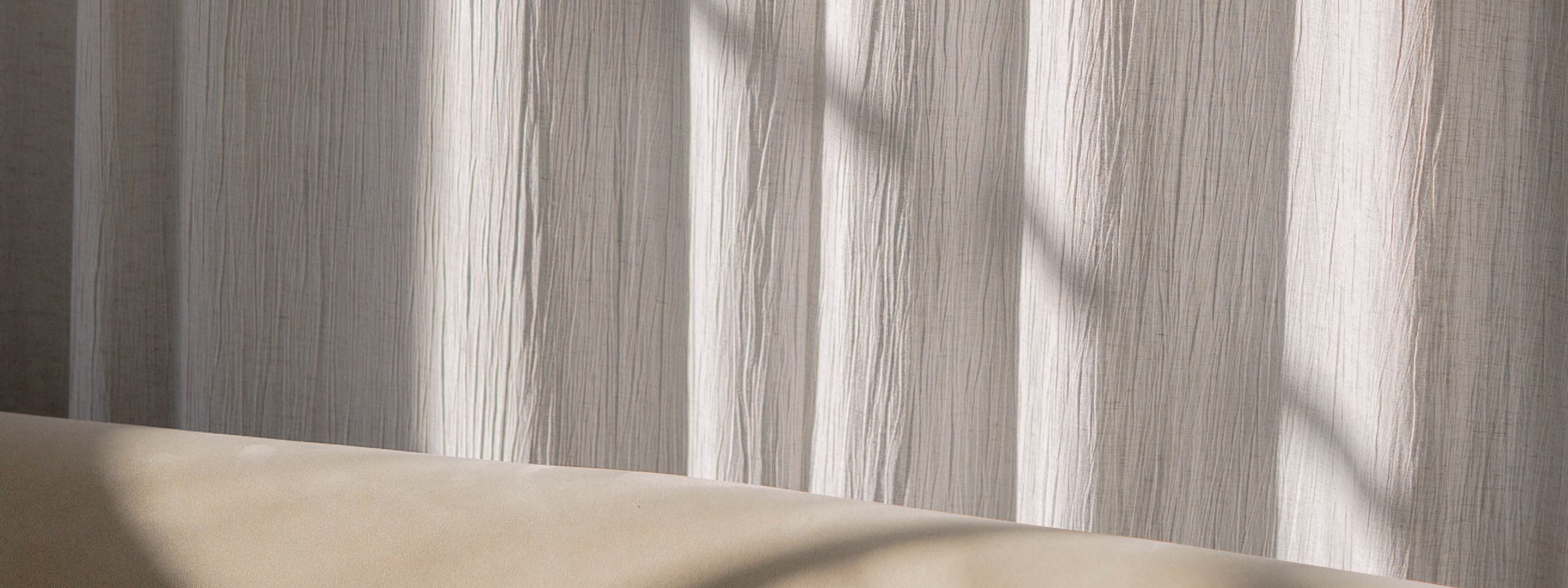 Soft light filtering through textured white curtains with neutral background
